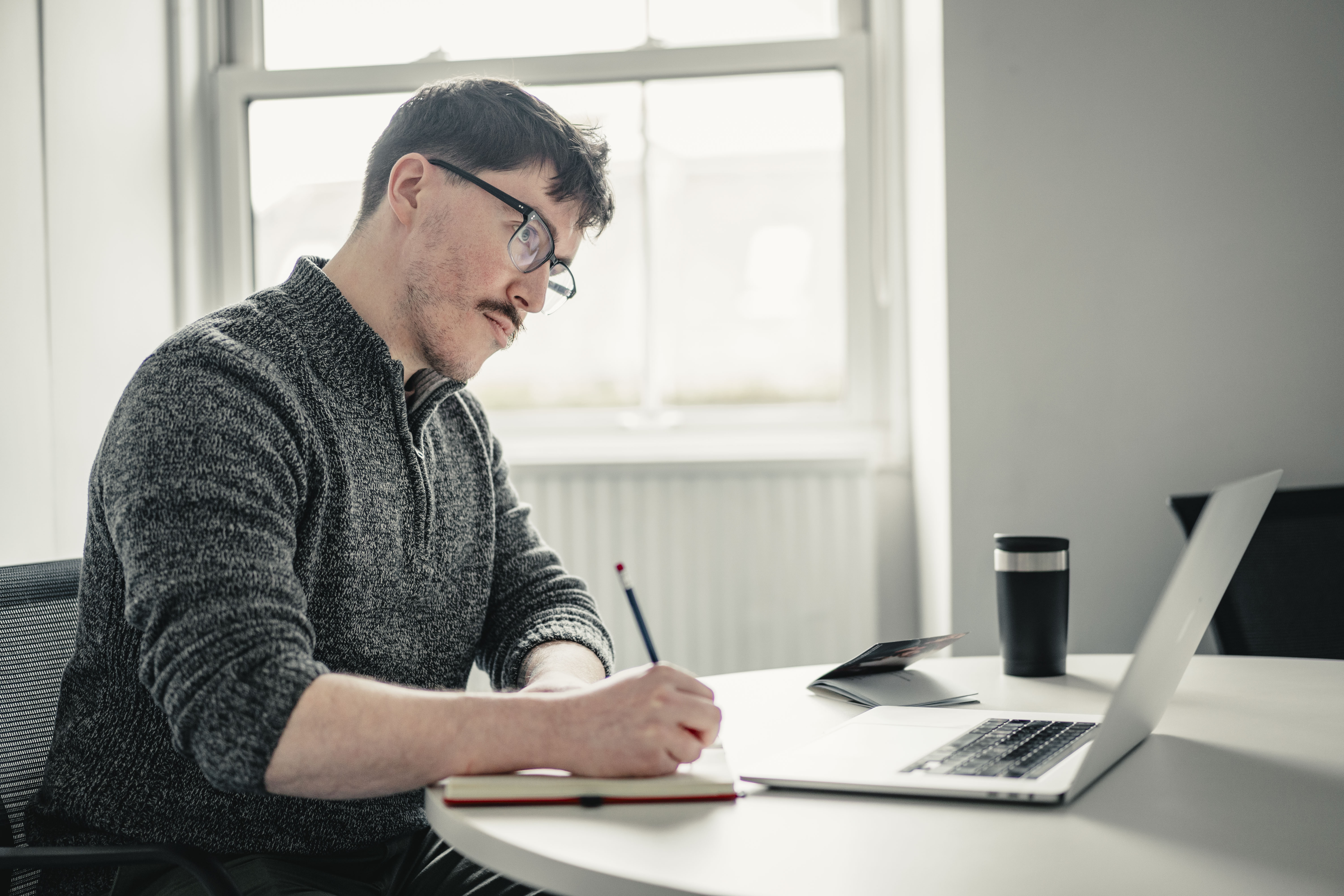 Man studying, taking notes from a laptop